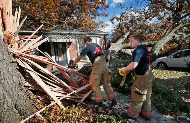 Webster Groves firefighters Chris Manita, center, and Matt Grossenhieder climb over a tree that fell on a house on Clydehurst Drive in Webster Groves, Mo., Sunday, Nov. 17, 2013.  The residents of the house were home at the time the tree fell but were not injured. Intense thunderstorms and tornadoes swept across a number of Midwestern states Sunday, causing damage in several central Illinois communities while sending people to their basements for shelter and even prompting officials at Soldier Field in Chicago to evacuate the stands and delay the Bears game. 